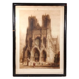 May include: An antique framed print of a cathedral, featuring intricate architectural details. The print is in sepia tones, with a black frame. The cathedral has two tall spires and a large arched entrance. The print is signed in the lower right corner.