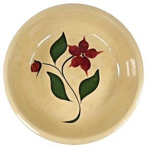 Puede incluir: Un cuenco de cerámica color crema con un diseño floral. El cuenco presenta una flor roja con hojas verdes y un tallo negro. El cuenco tiene un acabado brillante y un diseño simple y elegante.
