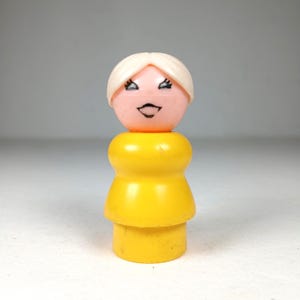 May include: A vintage Fisher-Price Little People figure. The figure has a pink head with a white hair, black eyes and a black smile. The body is yellow. This classic toy is a collectible item.