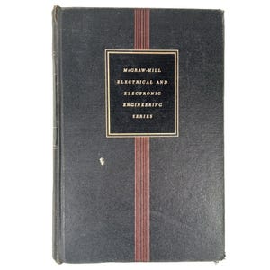 May include: A black hardcover book titled McGraw-Hill Electrical and Electronic Engineering Series. The front cover features a central rectangular label with gold text, framed by thin gold lines and vertical red stripes running down the center.