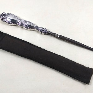 Peut inclure: Un chausse-pied en argent avec une poignée ornée et un étui en cuir noir.