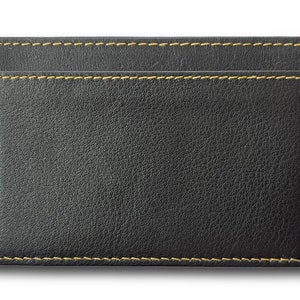 May include: A black leather card holder with yellow stitching. The holder has a single slot for cards.