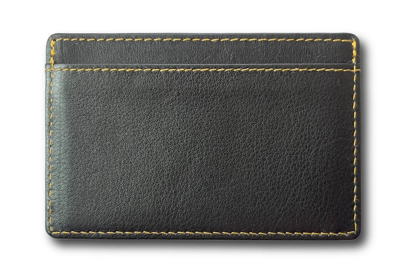 May include: A black leather card holder with yellow stitching. The holder has a single slot for cards.