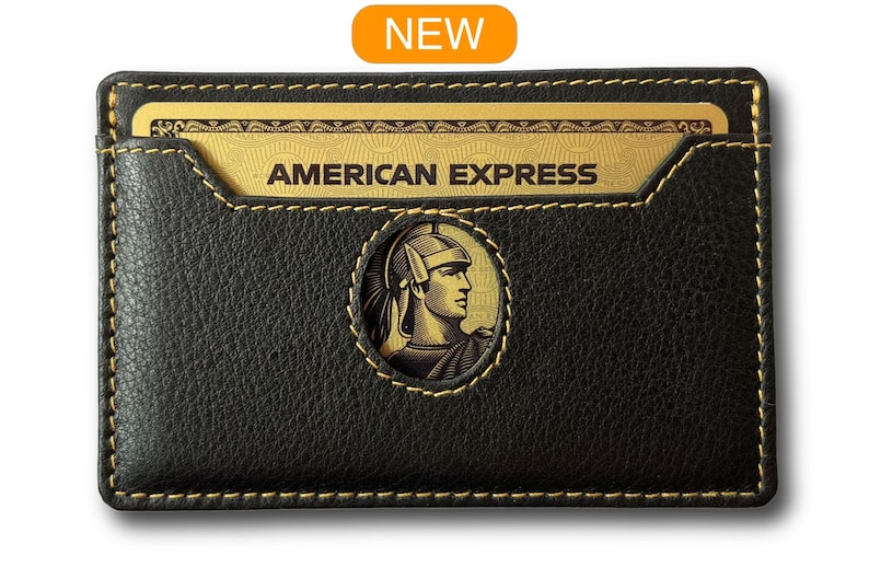 May include: Black leather card holder with a gold stitched border and a cutout for a gold American Express card. The card holder has a gold embossed logo of a Roman soldier's head.