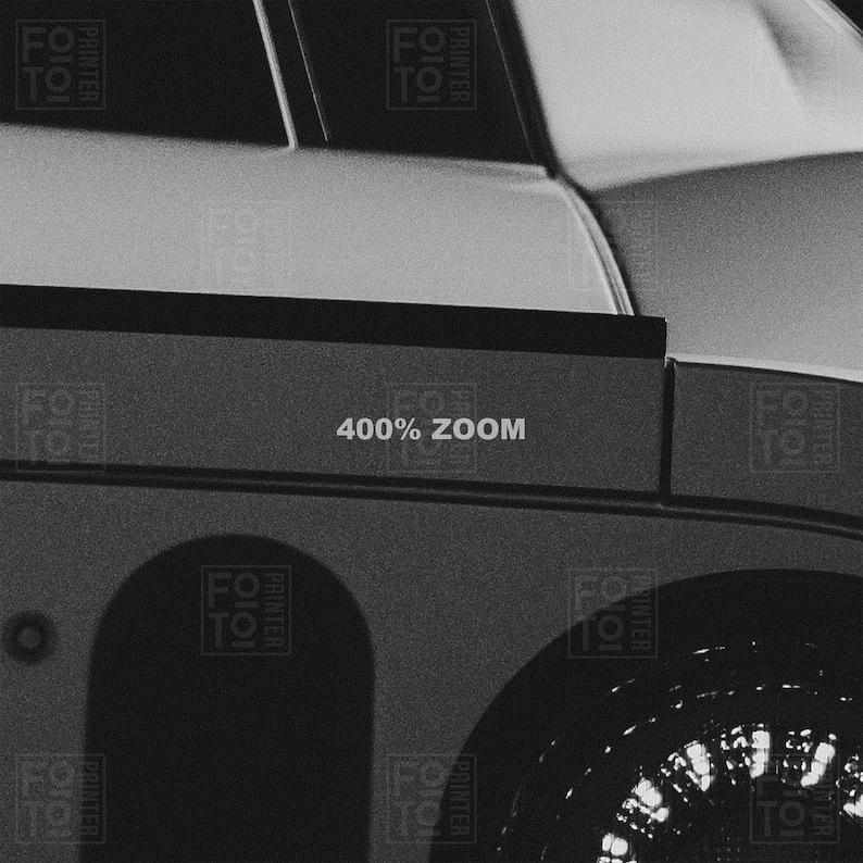 May include: Black and white image of a car's exterior, featuring a portion of the body, a wheel, and the text "400% ZOOM". The image is a close-up, highlighting the details of the vehicle's design.