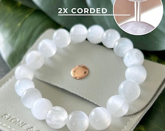 May include: White moonstone beaded bracelet with a white leather pouch. The bracelet has a 2x corded closure. The pouch has the text "Stone & Sonder" printed on it.
