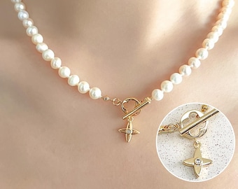 May include: A necklace featuring a strand of white pearls with a gold-toned toggle clasp. The clasp includes a circular ring and a bar, with a four-pointed star-shaped charm dangling from the center, featuring a small embedded clear stone.
