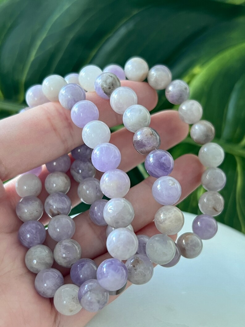 Puede incluir: Tres pulseras de amatista con cuentas redondas en tonos de morado y blanco.