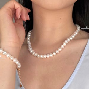 K&ouml;nnte beinhalten: Ein Set aus einer wei&szlig;en Perlenkette und einem passenden Armband mit runden Perlen von 8-8,5 mm Gr&ouml;&szlig;e. Die Schmuckst&uuml;cke sind aufgereiht und das Armband verf&uuml;gt &uuml;ber eine sichtbare Verschlussverl&auml;ngerung aus goldfarbenem Metall.