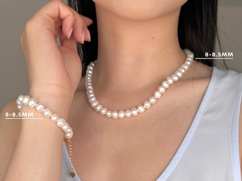 K&ouml;nnte beinhalten: Ein Set aus einer wei&szlig;en Perlenkette und einem passenden Armband mit runden Perlen von 8-8,5 mm Gr&ouml;&szlig;e. Die Schmuckst&uuml;cke sind aufgereiht und das Armband verf&uuml;gt &uuml;ber eine sichtbare Verschlussverl&auml;ngerung aus goldfarbenem Metall.