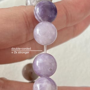Puede incluir: Un primer plano de un brazalete de amatista lavanda con cuentas redondas. El brazalete es de doble cord&oacute;n, lo que significa que es 2 veces m&aacute;s fuerte.