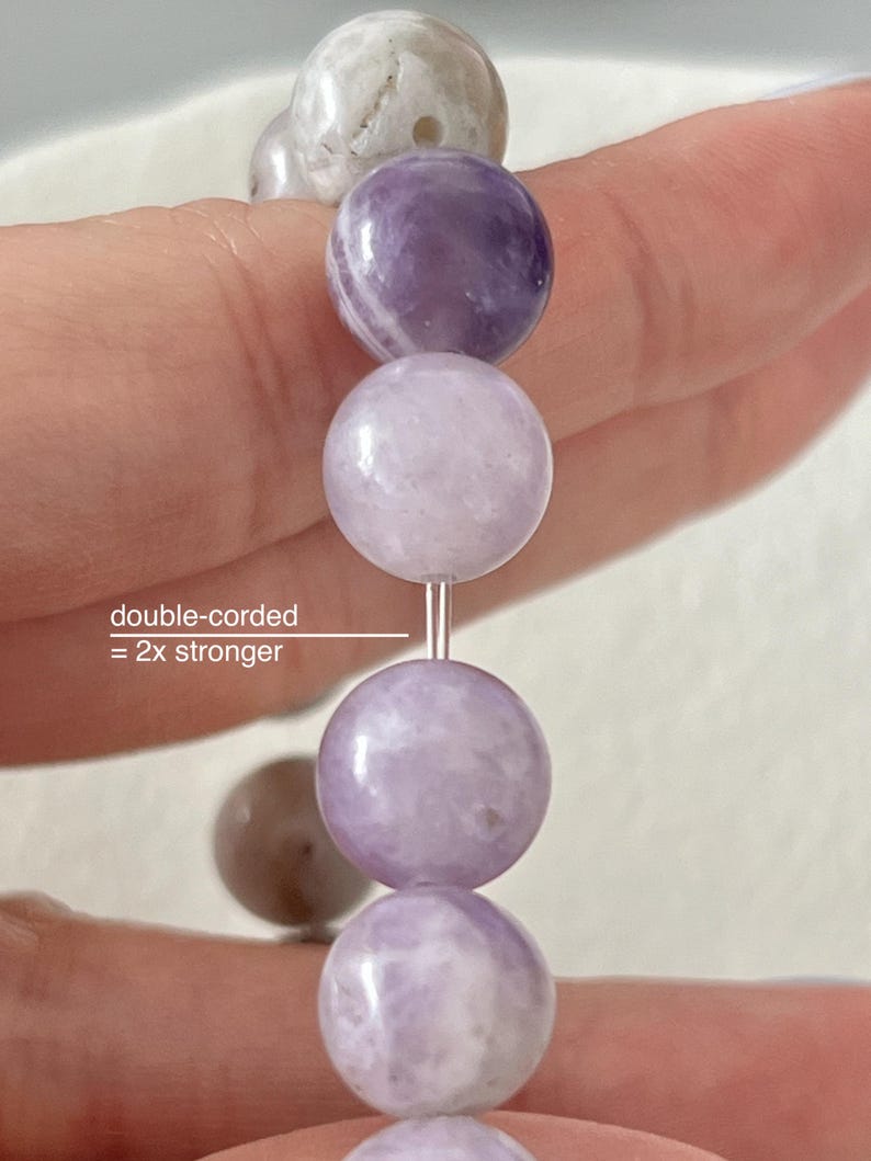 Puede incluir: Un primer plano de un brazalete de amatista lavanda con cuentas redondas. El brazalete es de doble cord&oacute;n, lo que significa que es 2 veces m&aacute;s fuerte.