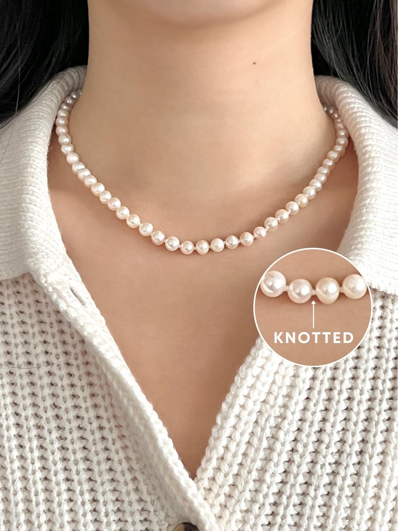 Individually knotted round pearl necklace on body with white knit cardigan sweater
