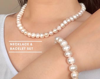 May include: A jewelry set consisting of a white pearl necklace and a matching white pearl bracelet. The text NECKLACE & BACELET SET is printed in white with horizontal lines above and below the words, displayed on a light-colored background.