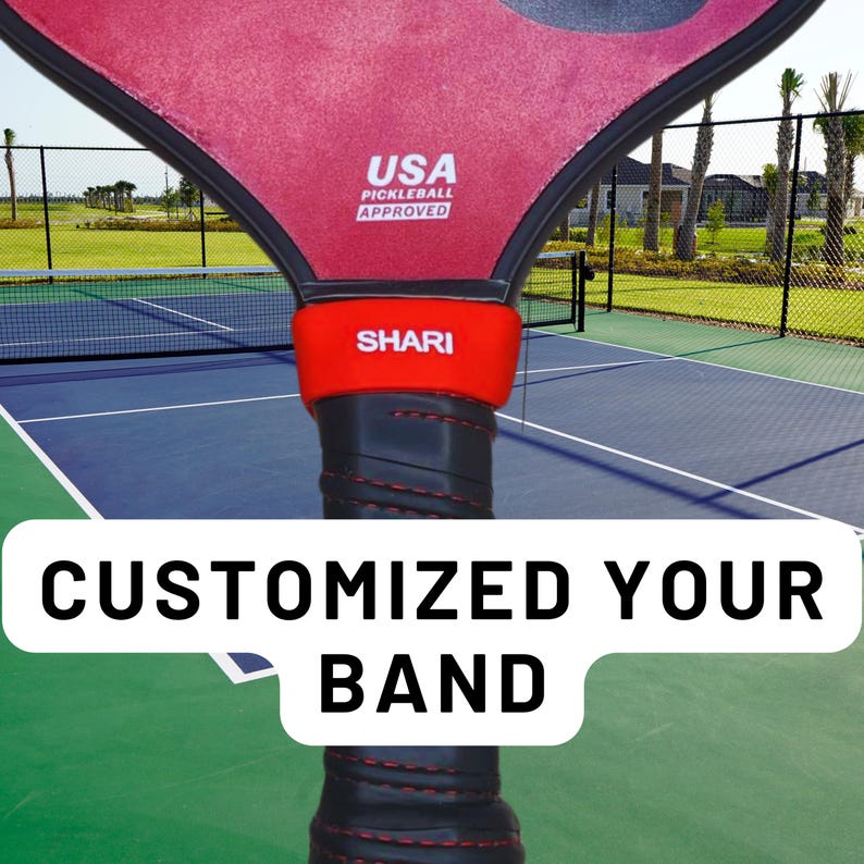 May include: A pickleball paddle featuring a red surface with the text USA PICKLEBALL APPROVED, a bright red silicone band with the white text SHARI, and a black handle with red stitching. A white overlay displays the text CUSTOMIZED YOUR BAND.