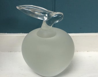 May include: A frosted glass apple-shaped decorative object with a clear, wing-like top. The apple has a smooth, matte finish, while the top is transparent. The object is likely a decorative piece or a unique art item.