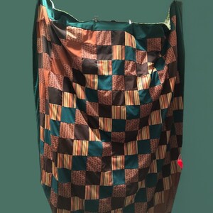 May include: A patchwork quilt with squares of brown, teal, and orange fabric. The quilt is made of different patterns and textures.