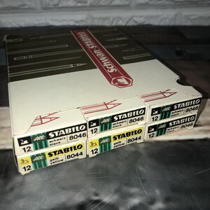 May include: A collection of STABILO All pencils in black and yellow, with the text "STABILO" and "8046" and "8044" printed on the boxes. The boxes are white, green, and yellow.