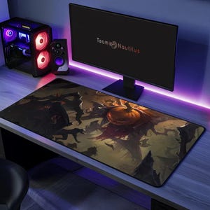 May include: A black and orange gaming mouse pad with a spooky Halloween design featuring a jack-o'-lantern and bats. The mouse pad has the text "Team Nautilus" printed on it.
