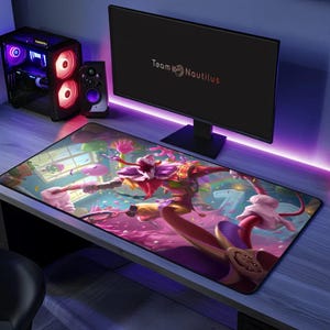 May include: A large rectangular gaming mouse pad featuring a colorful illustration of a character with a red and white face, wearing a jester-like outfit. The pad is on a desk with a computer monitor and speakers.