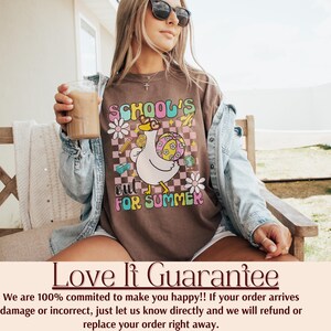 Pu&ograve; includere: T-shirt marrone con grafica retr&ograve; che recita "SCHOOL'S OUT FOR SUMMER". Il design presenta un'oca dei cartoni animati con occhiali da sole, che tiene in mano un pallone da spiaggia. La maglietta ha un aspetto vintage.