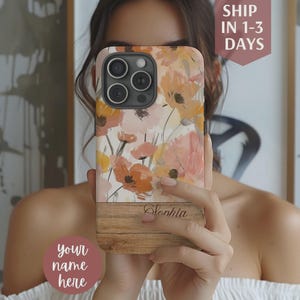 May include: A floral phone case featuring a watercolor design of orange and pink flowers. The case has a wooden-look bottom with the name "Sophia" printed on it. The text "your name here" is also visible.