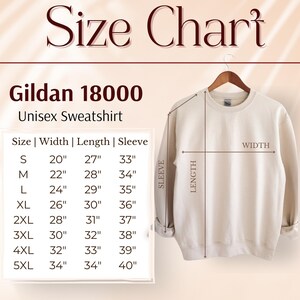 May include: A cream-colored Gildan 18000 unisex sweatshirt hangs on a wooden hanger. The image includes a size chart with measurements in inches for width, length, and sleeve length, ranging from size small to 5XL.