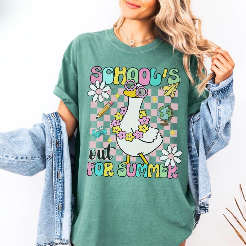 Pu&ograve; includere: T-shirt verde con la scritta "SCHOOL'S OUT FOR SUMMER" in un font retr&ograve;. La maglietta presenta un'oca dei cartoni animati con occhiali da sole e una ghirlanda di fiori, con grafica a tema scolastico.