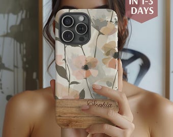 May include: A floral phone case with a wooden bottom. The case features a cream background with pink and gray flowers. The name "Sophia" is engraved on the wooden portion. The case is held in front of a person.