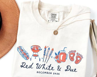 May include: Cream-colored t-shirt with a graphic design featuring a barbecue grill, fireworks, and a beverage. The text "Red White & Due December 2026" is printed below the graphics. A gold necklace is draped across the shirt.