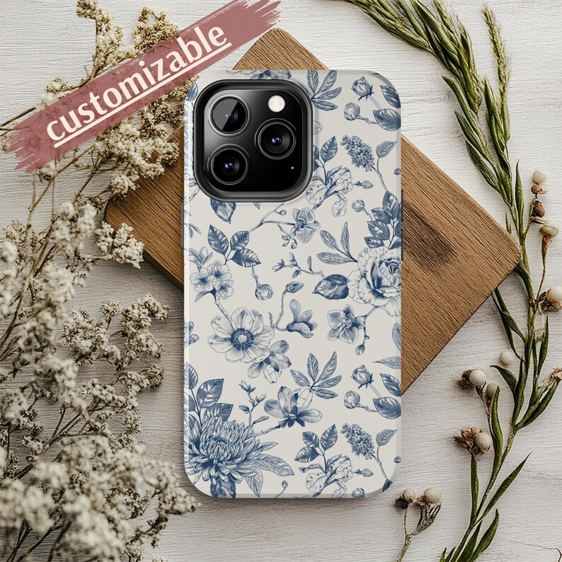 May include: A white phone case with a blue floral pattern. The case has a camera cutout and is customizable.