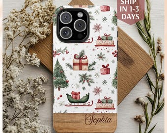 Puede incluir: Una funda de teléfono blanca con un diseño navideño festivo. Presenta ilustraciones en acuarela de regalos, copos de nieve, árboles de Navidad y un trineo. La parte inferior es de diseño de vetas de madera con el nombre "Sophia" grabado.