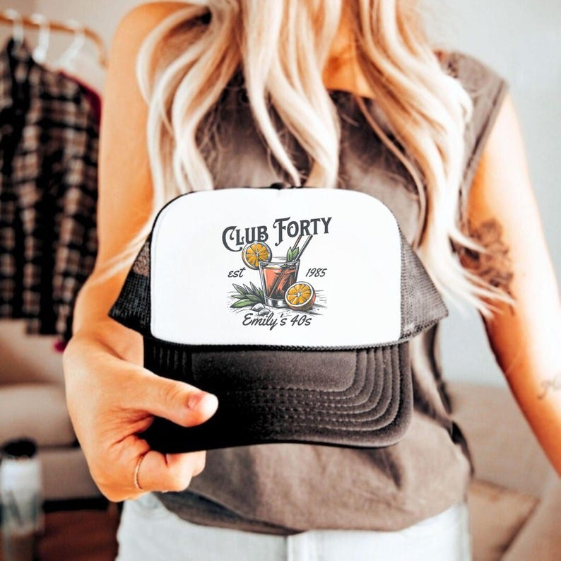 Puede incluir: Gorra de camionero negra y blanca con un panel frontal blanco que presenta un gr&aacute;fico de un c&oacute;ctel con el texto "Club Forty est 1985 Emily's 40s".