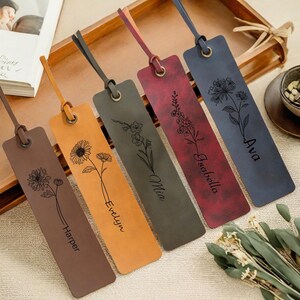 May include: Five leather bookmarks in shades of brown, orange, gray, red, and blue. Each bookmark features a floral design and a name: Harper, Evelyn, Mia, Isabella, and Ava. They have a loop at the top for a ribbon.