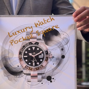Puede incluir: Un pañuelo de bolsillo blanco con una ilustración de un reloj negro y plateado. El reloj tiene una esfera negra con marcas blancas y una ventana de fecha. El texto "Luxury Watch Pocket Square" está escrito en naranja en el pañuelo de bolsillo.