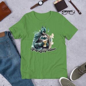 May include: Green short-sleeved t-shirt with a watercolor illustration of Batman holding a coffee cup. The text "All my Luxury Watches" is printed below the image.