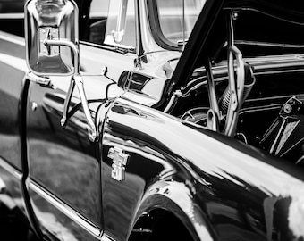 May include: Black and white photo of a classic pickup truck with the hood open. The truck has a chrome bumper, side mirrors, and a Chevrolet emblem on the fender.