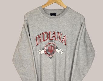 Może przedstawiać: Szara bluza z czerwono-białym logo Uniwersytetu Indiana i napisem "INDIANA" nad logo.