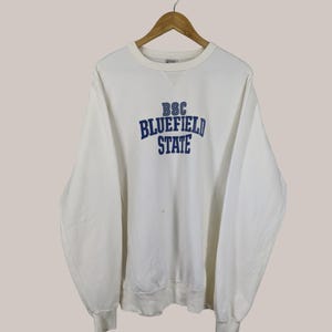Puede incluir: Sudadera blanca con un logotipo bordado en azul que dice "BSC Bluefield State"