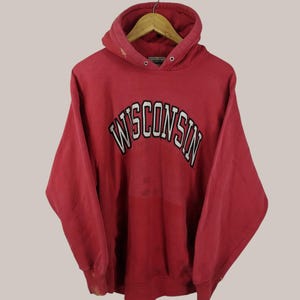 May include: Red hooded sweatshirt with the word "WISCONSIN" in white and black lettering on the front.