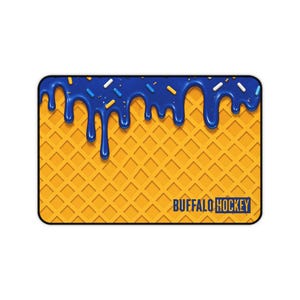 Puede incluir: Alfombrilla de ratón rectangular con un fondo de gofres y glaseado azul goteando desde la parte superior. El glaseado está decorado con chispas. Las palabras "BUFFALO HOCKEY" están impresas en la parte inferior.