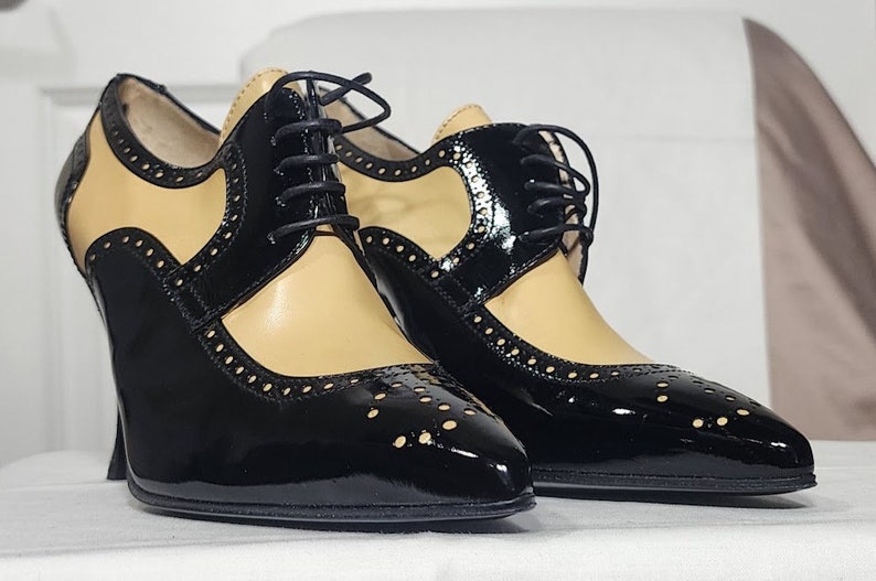 K&ouml;nnte beinhalten: Ein Paar schwarze und braune Lederschuhe mit Absatz, Schn&uuml;rung und Brogue-Muster.