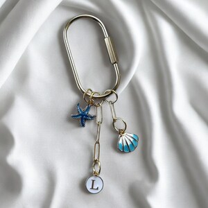 Preppy coastal bag charm featuring blue enamel seashell, starfish, and phrase ‘Last Toast On the Coast’—great as bridal party favor or destination wedding keepsake