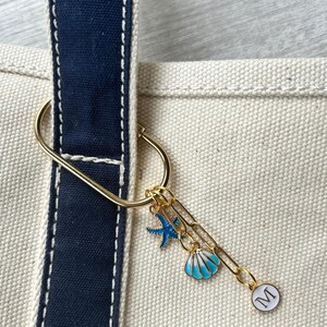 Personalized beach tote charm reading ‘Last Toast On the Coast’, with blue shell and starfish accents on a gold clip—cute accessory for cruise bags or BFF gifts