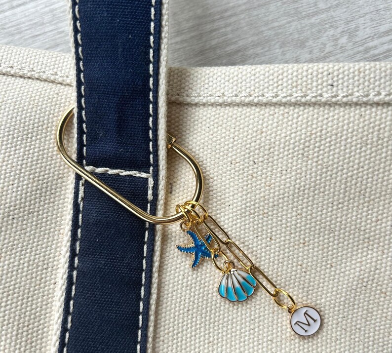 Personalized beach tote charm reading ‘Last Toast On the Coast’, with blue shell and starfish accents on a gold clip—cute accessory for cruise bags or BFF gifts