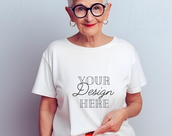 Könnte beinhalten: Eine Frau trägt ein weißes T-Shirt mit dem Aufdruck "YOUR Design HERE" auf der Vorderseite. Sie trägt außerdem eine orangefarbene Hose und hat kurze graue Haare.