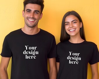 May include: Two people wearing black t-shirts with the text "Your design here" printed in white on the front. The people are standing in front of a yellow background.
