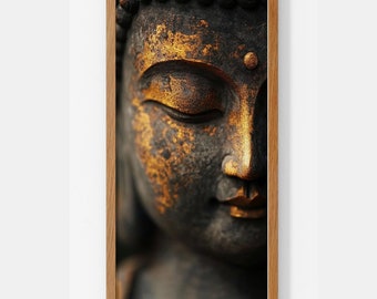 May include: Close-up of a golden Buddha statue with closed eyes. The statue is made of dark brown stone with gold accents. The image is framed in a light brown wood frame.