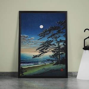 Puede incluir: Impresi&oacute;n art&iacute;stica enmarcada que representa una escena costera iluminada por la luna con un gran pino. La obra presenta un cielo azul oscuro, una luna llena y una playa con suaves olas. A la derecha hay una l&aacute;mpara negra con una pantalla blanca.