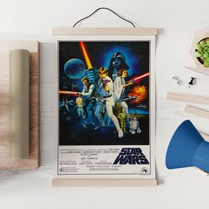 Może przedstawiać: Winietyczny plakat filmu Gwiezdne Wojny przedstawiający grupę postaci z filmu, w tym Luke'a Skywalkera, Hana Solo, księżniczkę Leię, Chewbakkę i Dartha Vadera. Plakat umieszczony jest na ciemnoniebieskim tle z gwiazdami i planetami. Tytuł "Gwiezdne Wojny" wyświetlany jest ż&oacute;łtymi literami na dole plakatu.